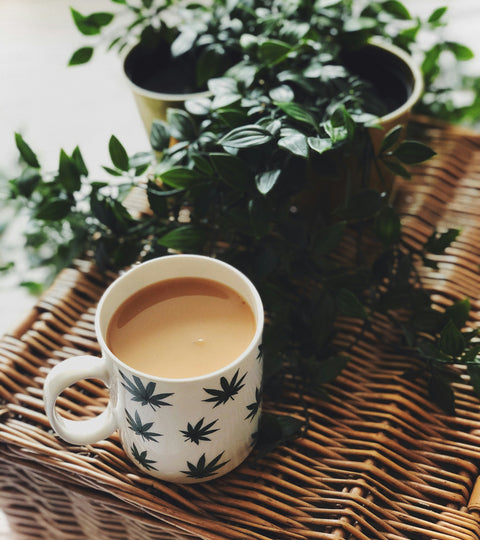 ceramic cup of coffee with leaves adorning it sitting on a wicker table